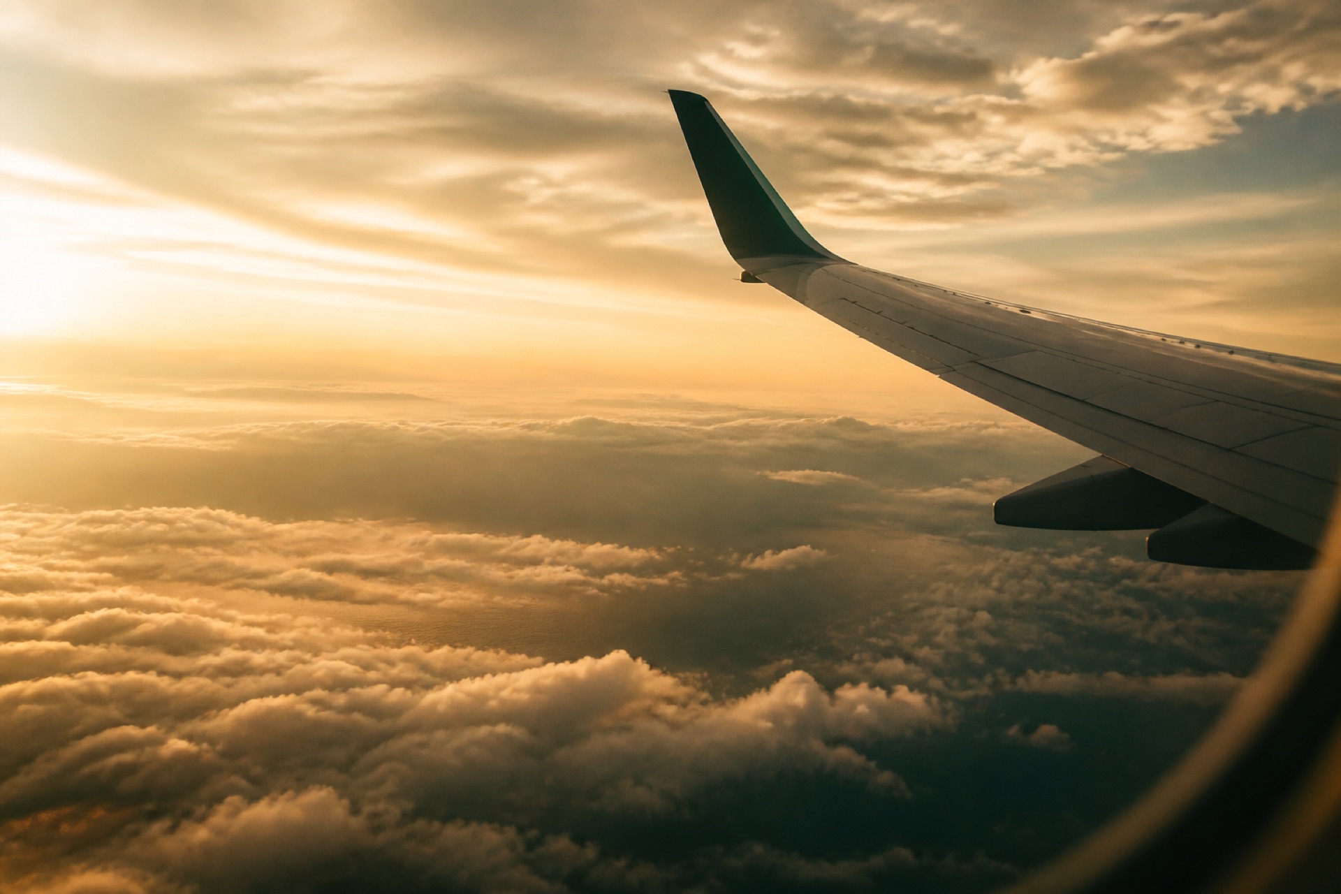 Asa de avião ao entardecer, sobre as nuvens